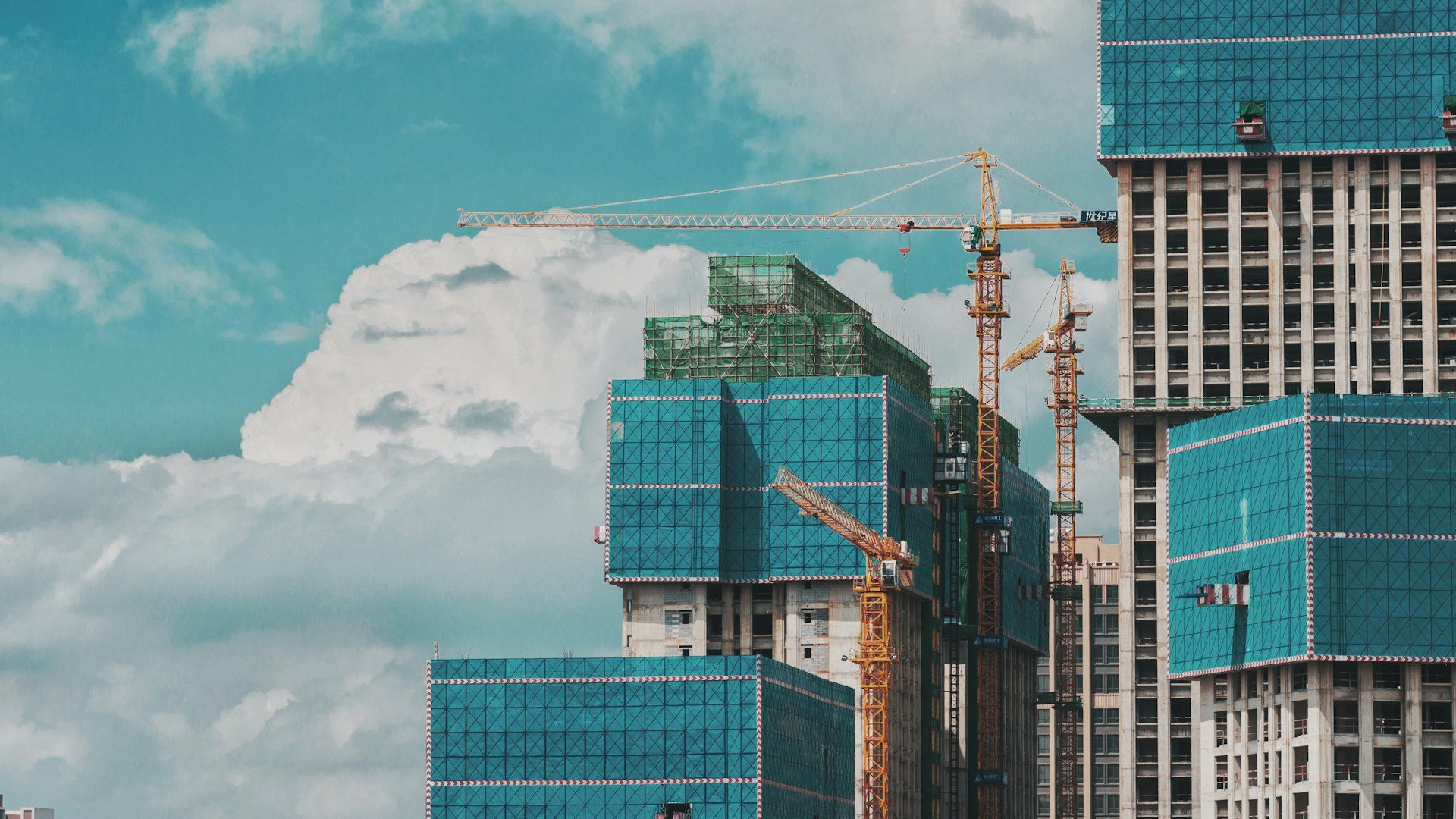 Construction cranes and a building rising against the sky